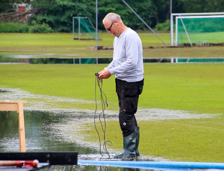 Vaktmästare BG Hansson fixar med pumpar som ska torka upp planen. Foto: Peter Jakobsson