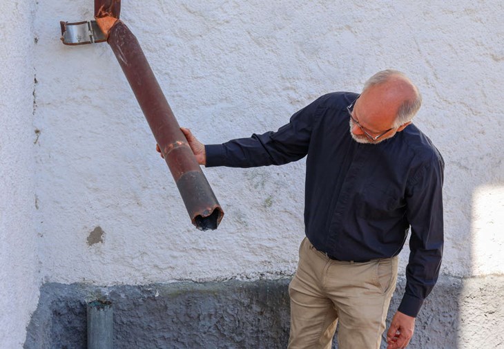 Hans Eriksson tittar på en bit av ett stuprör som tjuvarna försökt slita loss men inte lyckats. Foto: Peter Jakobsson